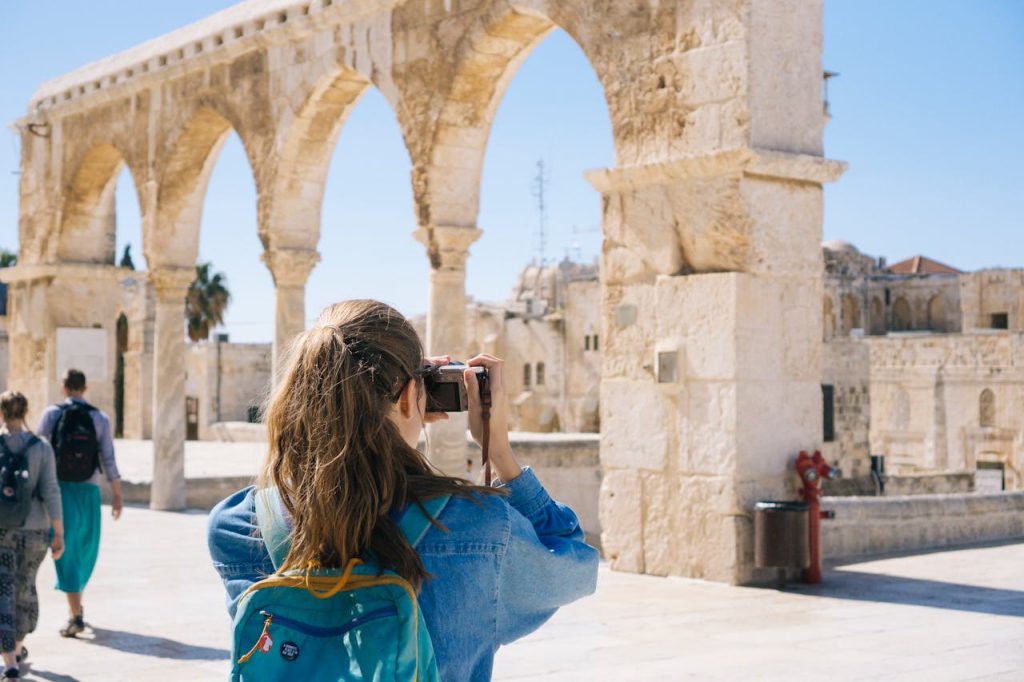 A tourist photographs the ancient stone arches in Jerusalems Old Town, capturing the essence of travel and history.